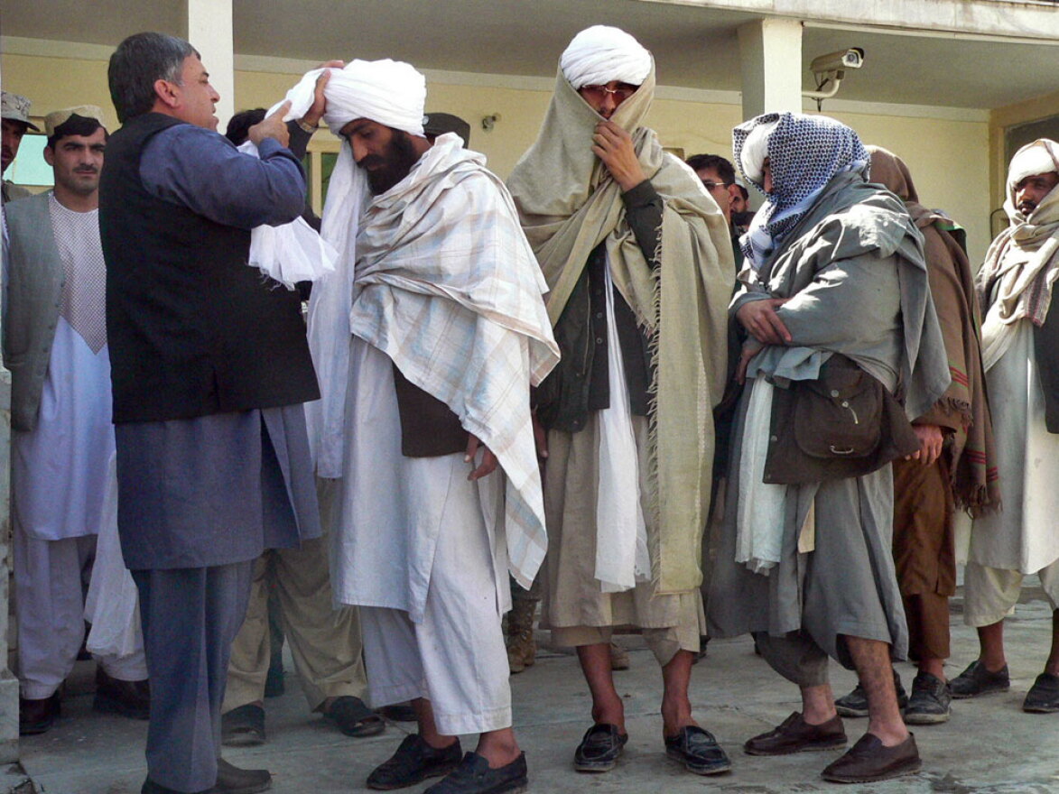 Kandahar Gov. Tooryalai Wesa, left, puts a turban on former Taliban fighter Malawi Azizullah.